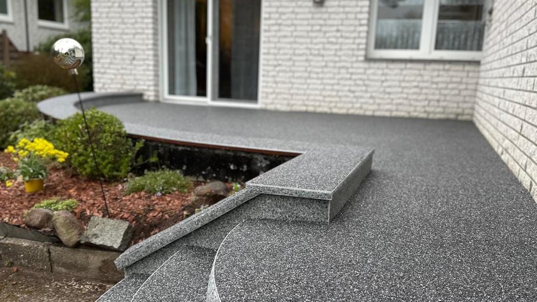 Geschwungene Terrasse mit Steinteppich und Sitzplatz